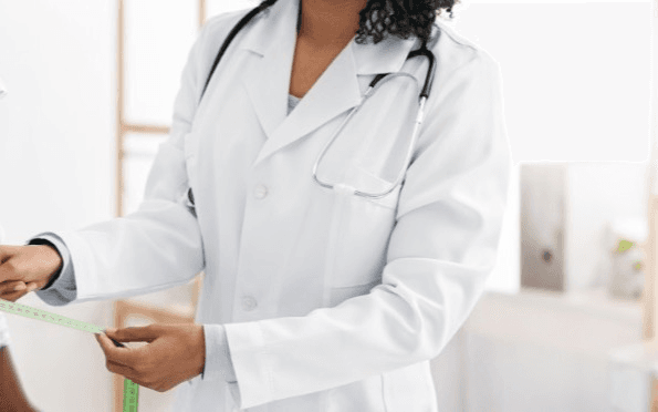 Doctor measuring a patient's waist with a tape measure in a clinical setting